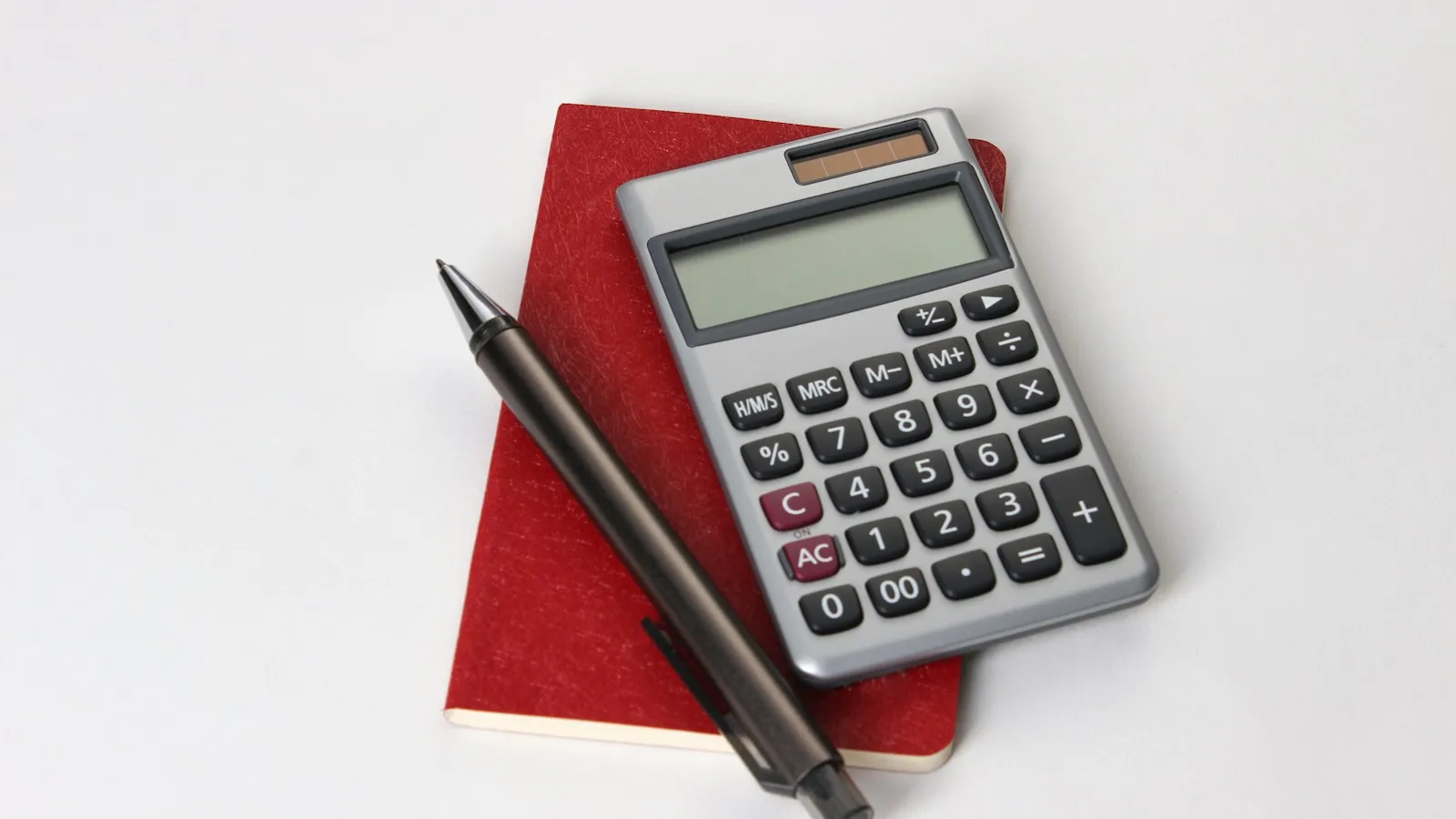 Calculator and pen resting on a red notebook