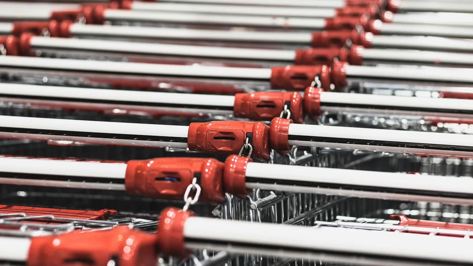 Rows of shopping carts with red handles lined up at a store
