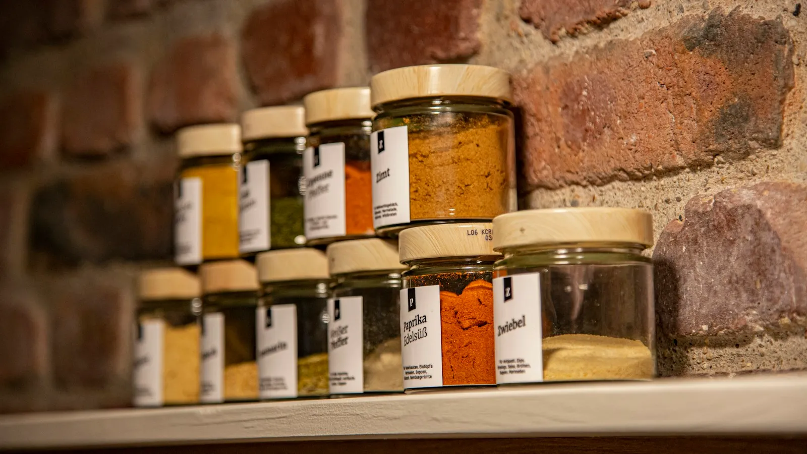 Glass spice jars with paper labels on a shelf
