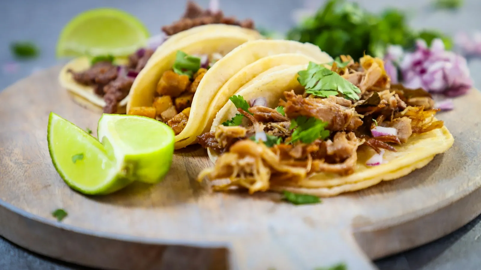 Tacos with lime wedges on a wooden board