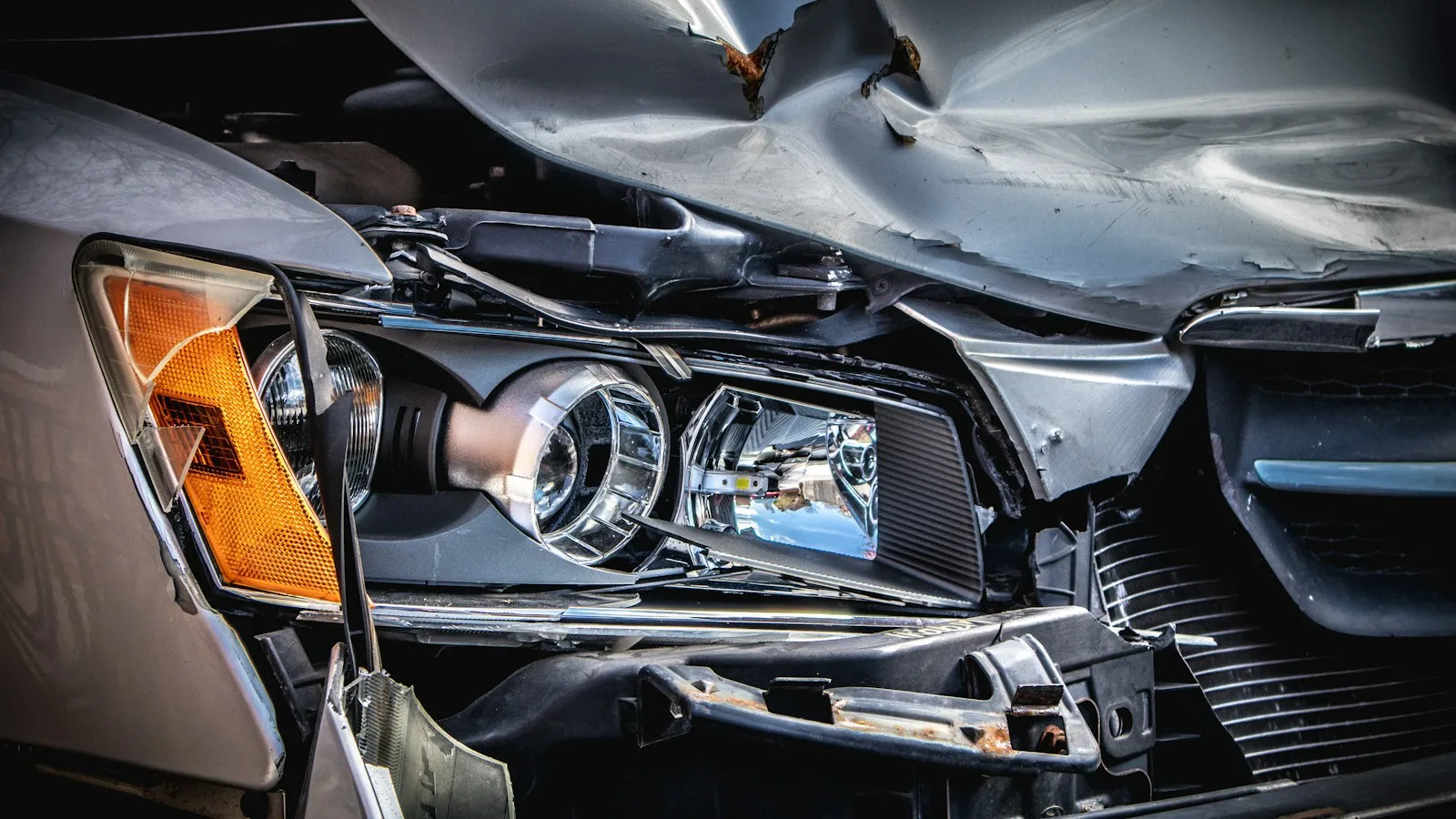 Front of a car crushed in a crash, with a broken headlight