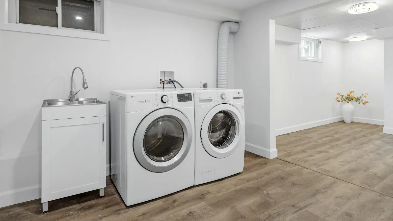 A washer and dryer side by side in a bright, clean basement laundry room