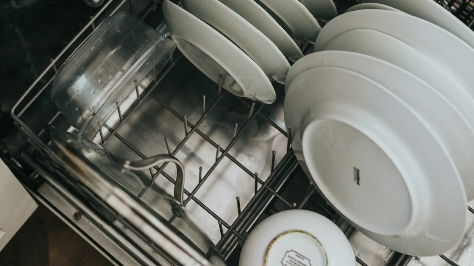 Clean white plates stacked in the lower rack of an open dishwasher